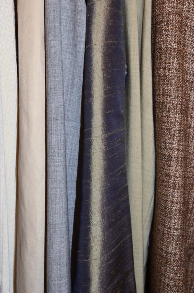 A collection of diverse fabric textures and patterns hung vertically, illustrating textile variety.