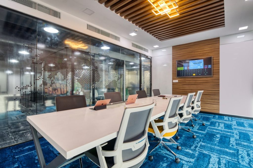 Sleek, contemporary office boardroom with glass walls, modern furniture, and digital screen display.